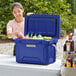 A woman putting beverages in a CaterGator outdoor cooler.