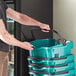 A man pushing a stack of Regency Green plastic grocery market baskets with wheels.
