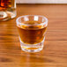 A GET SAN plastic shot glass filled with brown liquid on a table.