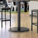 A Lancaster Table & Seating standard height table base column on a table with a cup and a plate.