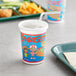A Royal Paper plastic cup with a lid and straw on a table with food.