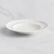 A RAK Porcelain ivory deep plate with an embossed wide rim on a white surface.