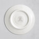A white porcelain saucer with an embossed logo.