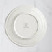 A white RAK Porcelain flat plate with an embossed crown on the rim.
