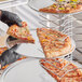 A person in black gloves holding a pizza on a Choice aluminum pizza pan.