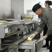 A man putting food in a Traulsen refrigerated chef base drawer in a commercial kitchen.