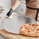 A person holding a pizza on a Choice aluminum pizza pan.