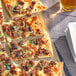 A square pizza topped with Regal Mild Sweet Italian Sausage seasoning and olives on a tray.