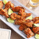A plate of Regal Maple Chipotle chicken wings with lime wedges.