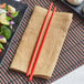 A plate of vegetables with Emperor's Select red melamine chopsticks on a mat.