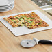 A square pizza with broccoli and cheese on a white corrugated square board.