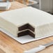 A white cake with two layers on a white corrugated half sheet cake board.