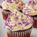 A close-up of a cupcake with purple and white sprinkles, including Bake-Stable Purple Sprinkles.
