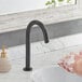 A person washing their hands with soap under a Waterloo matte black hands-free sensor faucet.