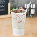 A Solo wax treated paper cold cup filled with iced coffee and a straw.
