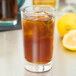 A close up of a Libbey highball glass filled with iced tea and a lemon slice.