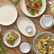A table set with white Acopa stoneware bowls, plates, and utensils.