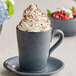 A close up of a cup of coffee with whipped cream and sprinkles in an Acopa Embers midnight blue stoneware mug.