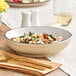 An Acopa Harvest Tan stoneware pasta bowl filled with pasta and mushrooms on a table.