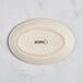 An Acopa cream white matte coupe stoneware platter with black text reading "Acopa" on the bottom.