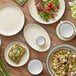 A table set with Acopa cream white stoneware platters, bowls, and plates with black rims.
