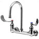 A T&S chrome wall mounted surgical sink faucet with two wrist action handles and a gooseneck spout.