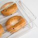 A Cambro clear dome display cover over a glass container of bagels.