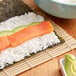 A bowl of sushi rice with a piece of salmon and avocado.