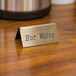 A gold Cal-Mil hot water beverage tent sign on a table.