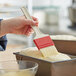 A person using a Choice natural bristle pastry brush to spread dough in a pan.