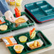 A right handed Choice forest green melamine tray with food in it.
