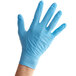 A hand wearing blue Medique nitrile gloves.