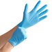 A pair of hands wearing blue Medique nitrile gloves.