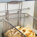 A Grindmaster-Cecilware fryer basket filled with french fries on a counter.