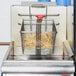 A Grindmaster-Cecilware fryer basket filled with fries in a deep fryer.
