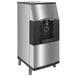 A stainless steel Manitowoc touchless ice dispenser with a black door.