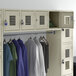 A Regency beige wall mount locker with clothes hanging inside.
