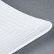 A close-up of a white GET Milano square melamine plate with a curved edge.