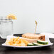A Milano white square melamine plate with a sandwich, fries, and a glass of water.
