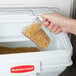 A hand pouring pasta into a Rubbermaid ingredient storage bin.