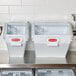 Two Rubbermaid white ingredient bins with sliding lids on a stainless steel counter.