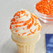 An ice cream cone with orange sprinkles.