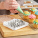A person using a Choice stainless steel piping tip to decorate cupcakes.