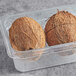 A pair of brown coconuts in a plastic container.