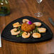 A black Elegance Triangle melamine plate with shrimp on a table.
