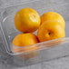 Fresh sour oranges in a plastic container on a table.