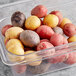 A plastic container of mixed marble potatoes including red, yellow, and purple varieties.