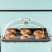 A Cal-Mil Classic dome cover with a tray of bagels and a clear handle.