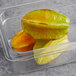 A plastic container with three starfruit in it.