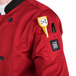 A Chef Revival tomato red chef jacket with a pen and a measuring device in the pocket.